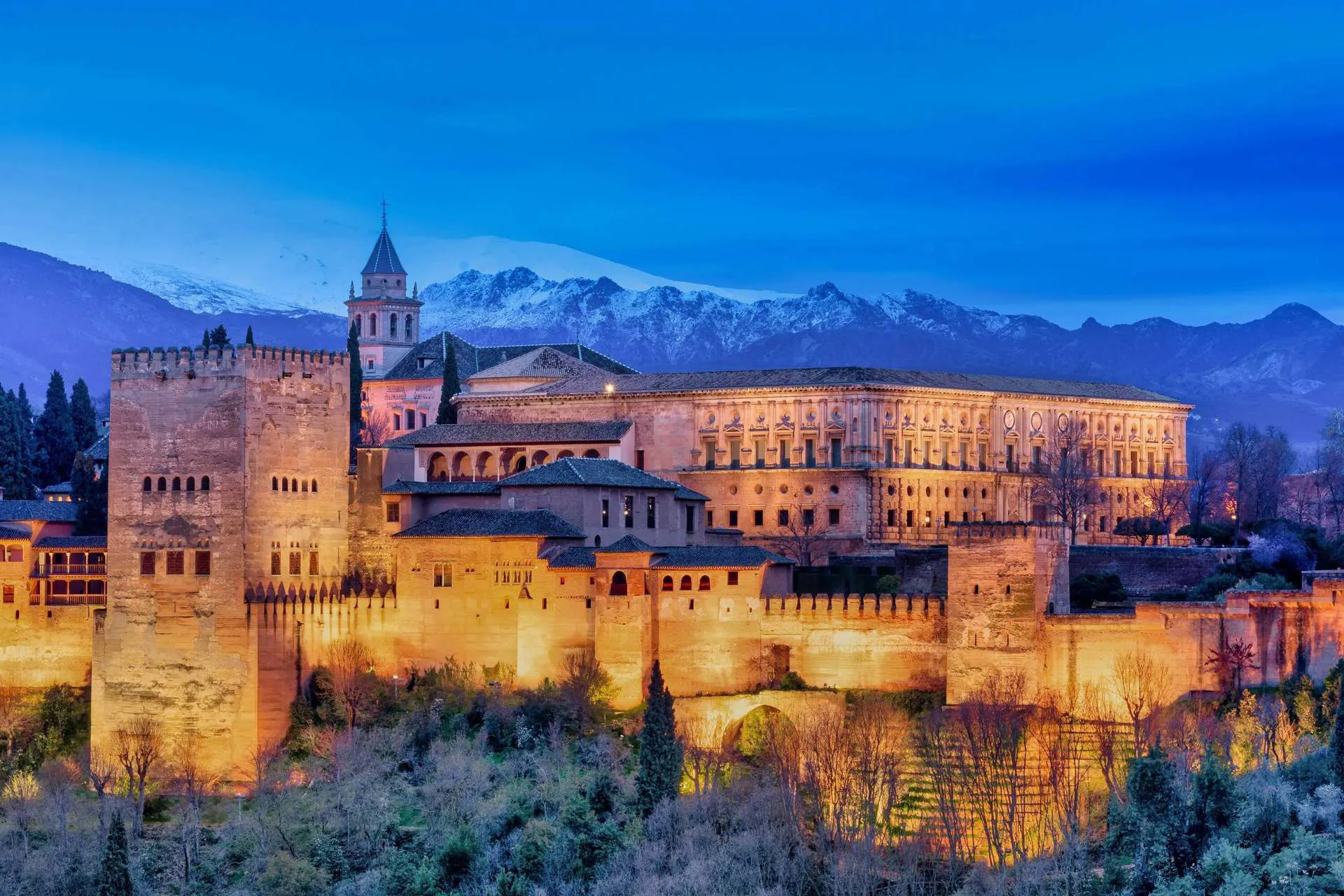 Architectural castles and buildings lit up at night in Andalucia.