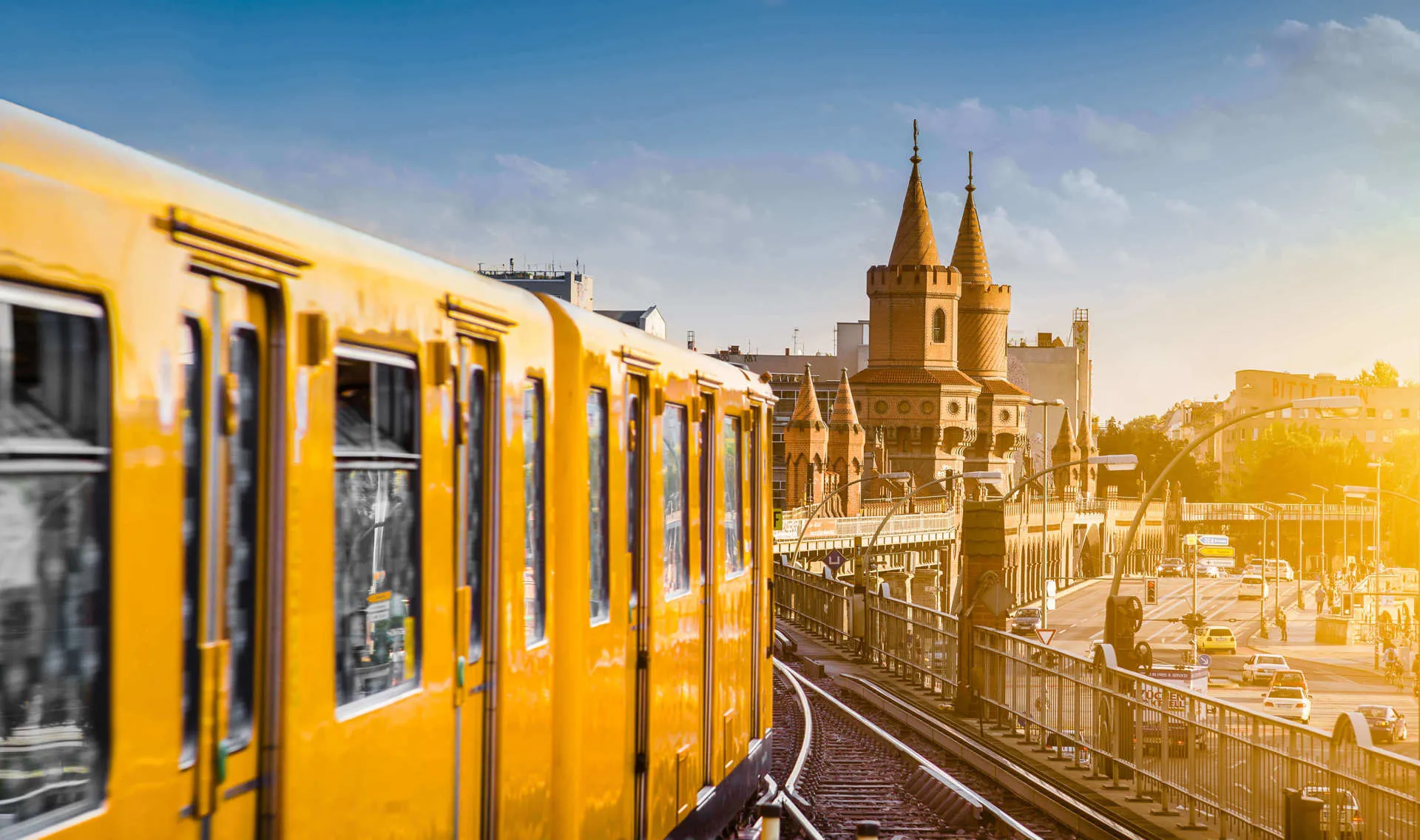 A yellow train passes over a bridge overlooking the city of Berlin.