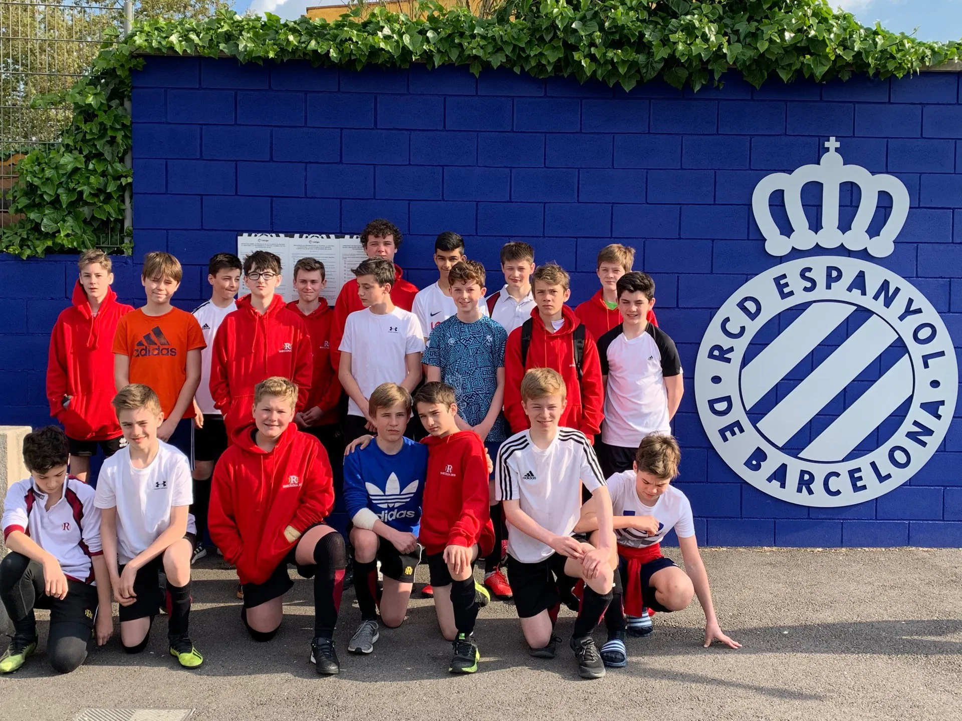 A group of students dressed for football posing next to a wall with the RCD Espanyol De Barcelona logo
