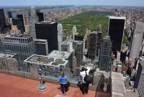 2 people stood on top of a building overlooking NYC and Central Park.