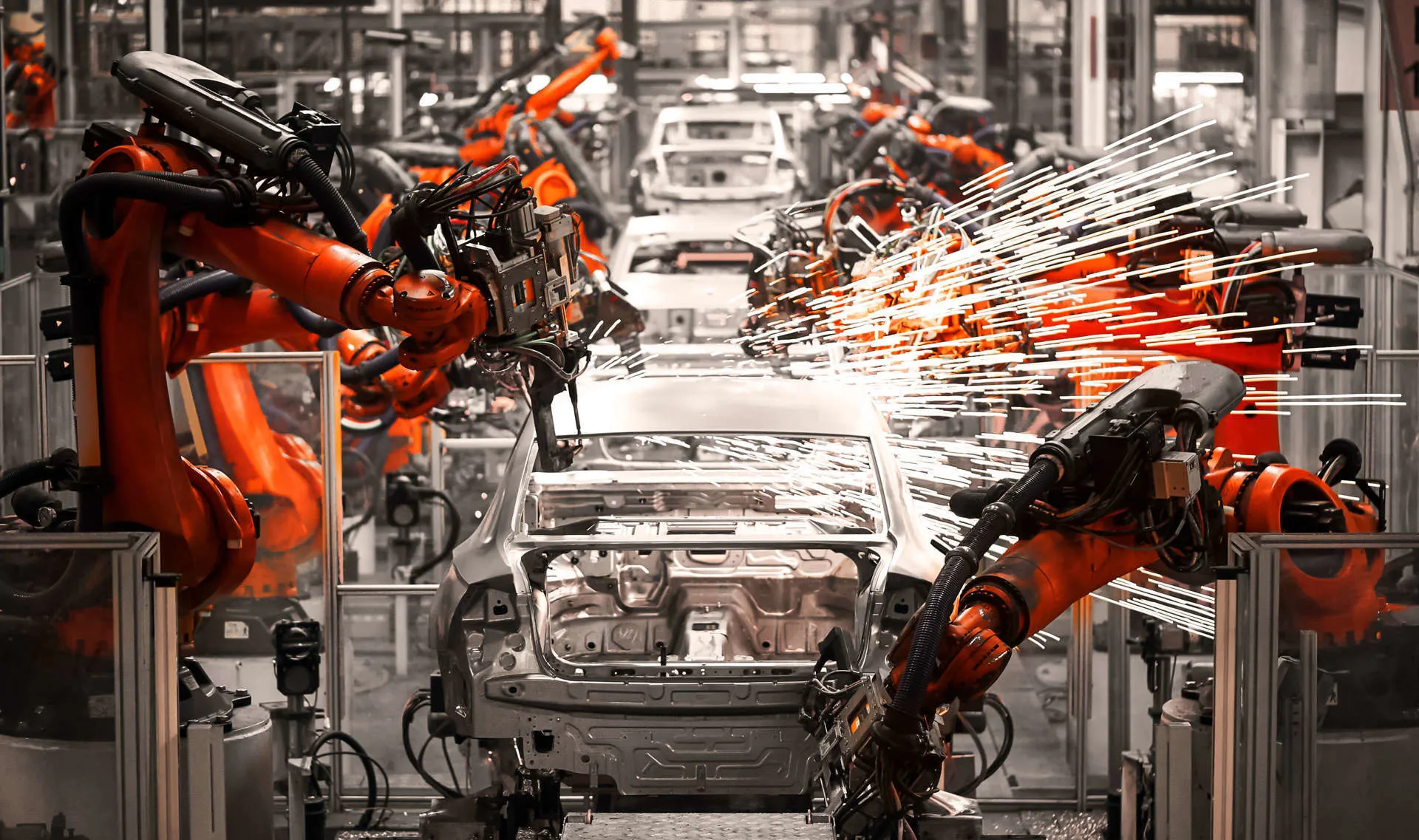 Machinery and robotics operate on metal shells of cars in a car factory in Berlin, Germany.