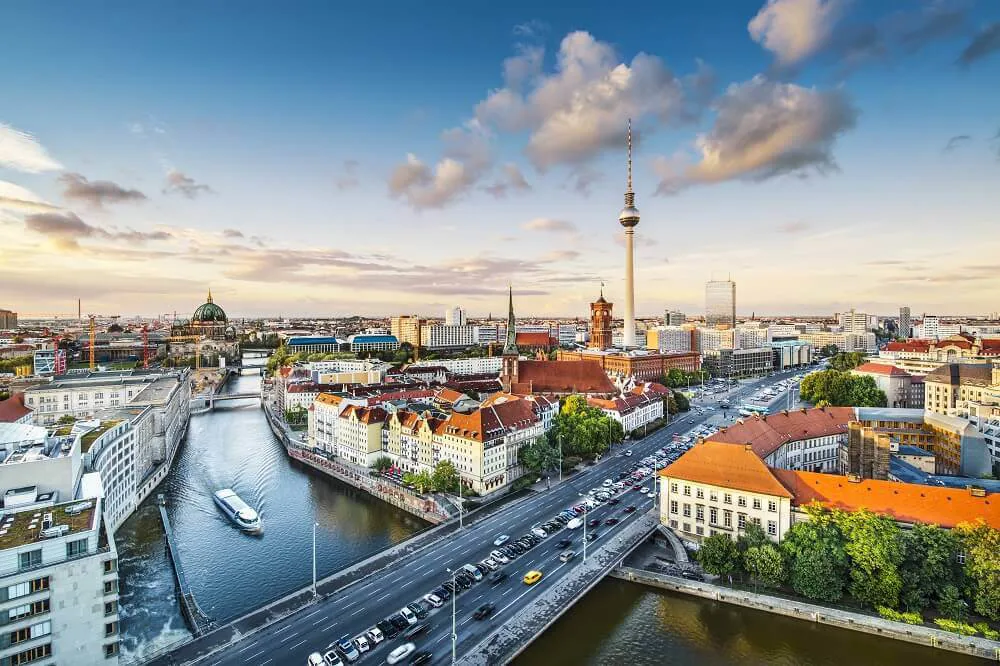 A panoramic view of Berlin, showing riverboats pass along the river and the Television tower in the distance.