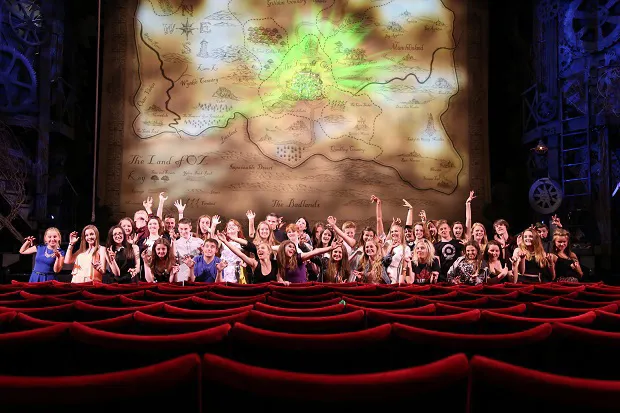 School group posing in front of the Wicked stage at the Apollo Theatre London
