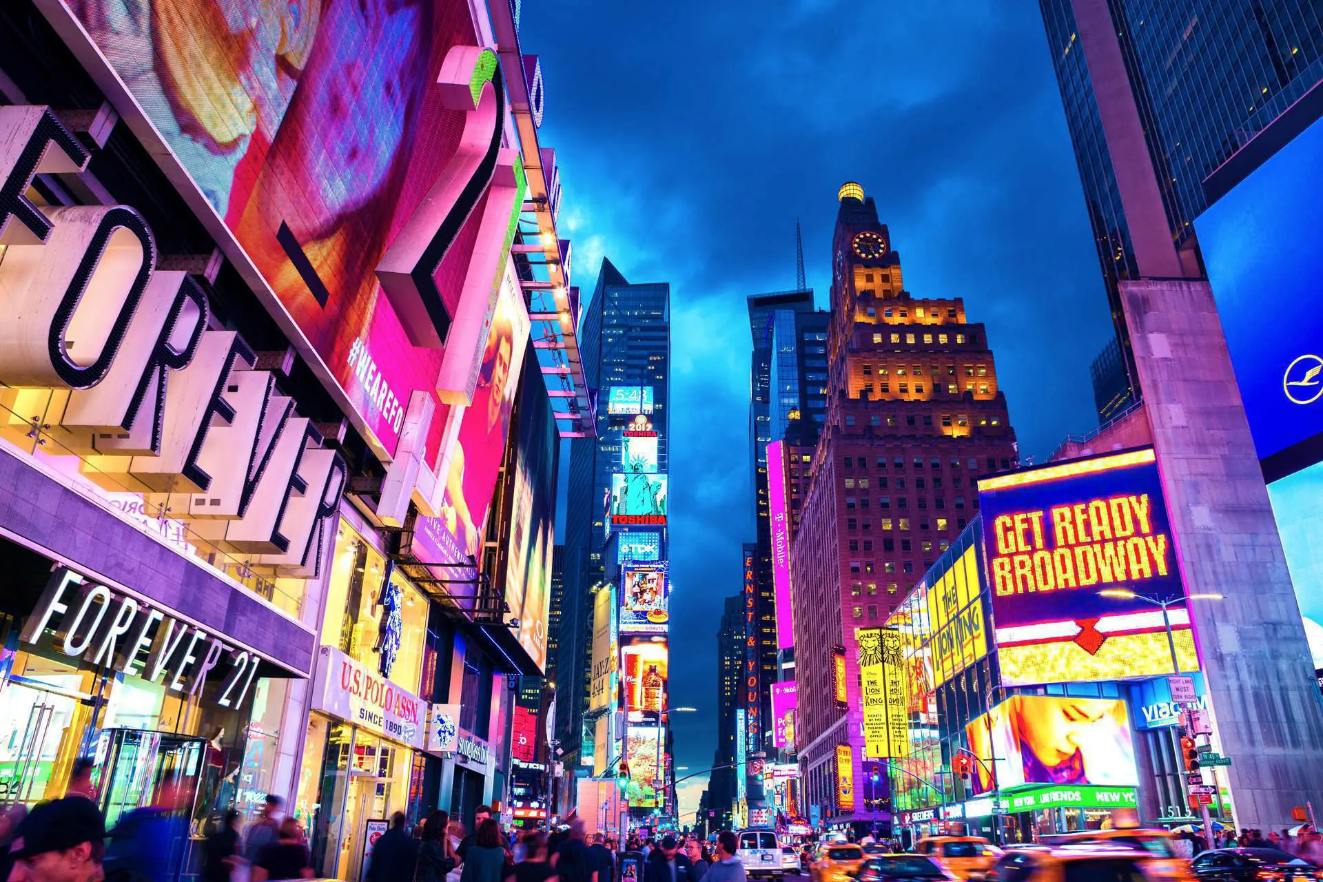 A busy night in Times Square with signage saying "Get Ready Broadway".