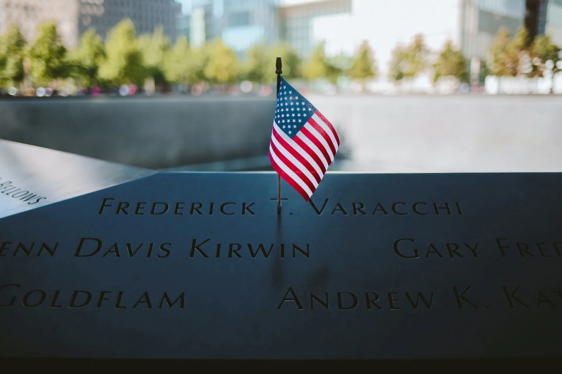 An American flag on a memorial plaque of 9/11 victims at the 9/11 Memorial in New York City, USA.