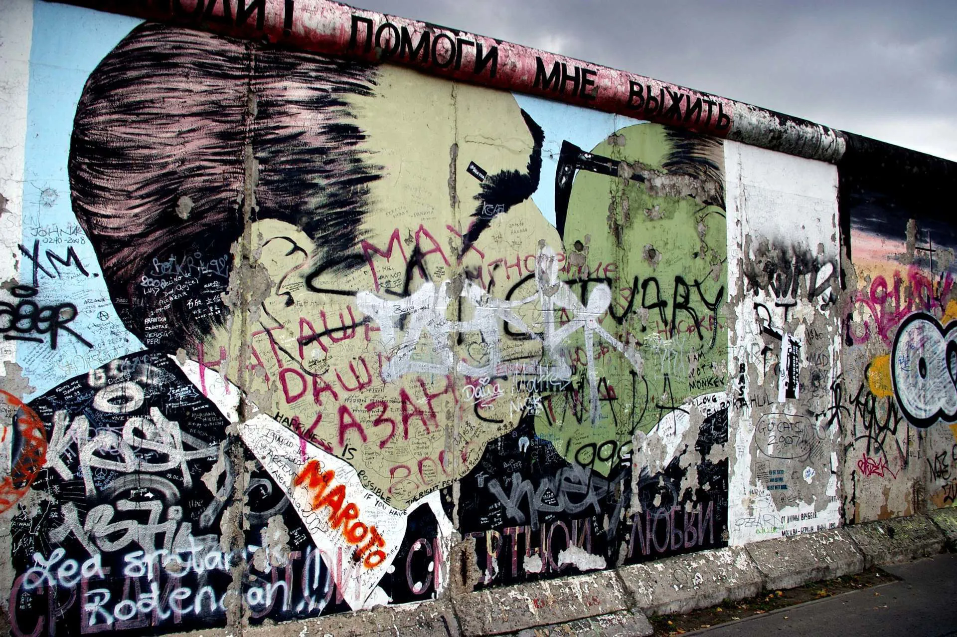 Street art and graffiti depicting the side profile of a man wearing a suit on the Berlin Wall.