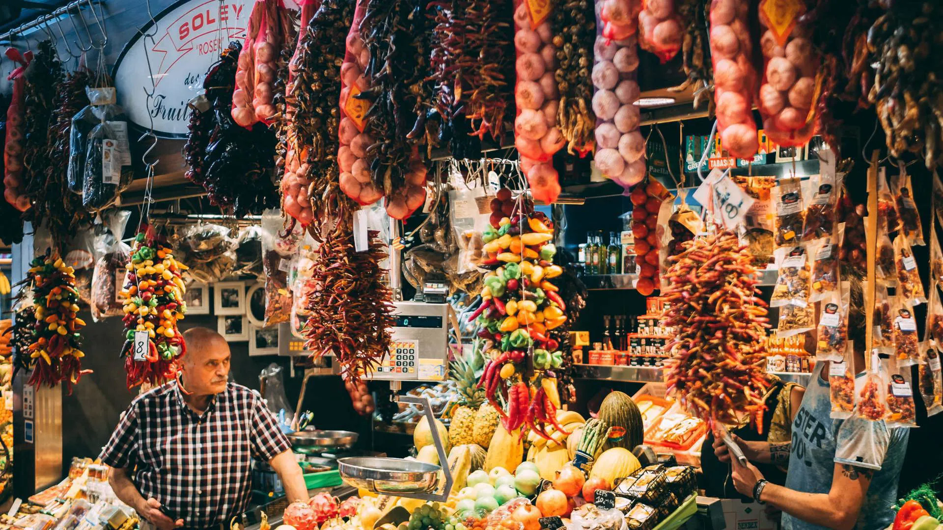 Onions, garlic, and a shopkeeper at a market stall in Barcelona.