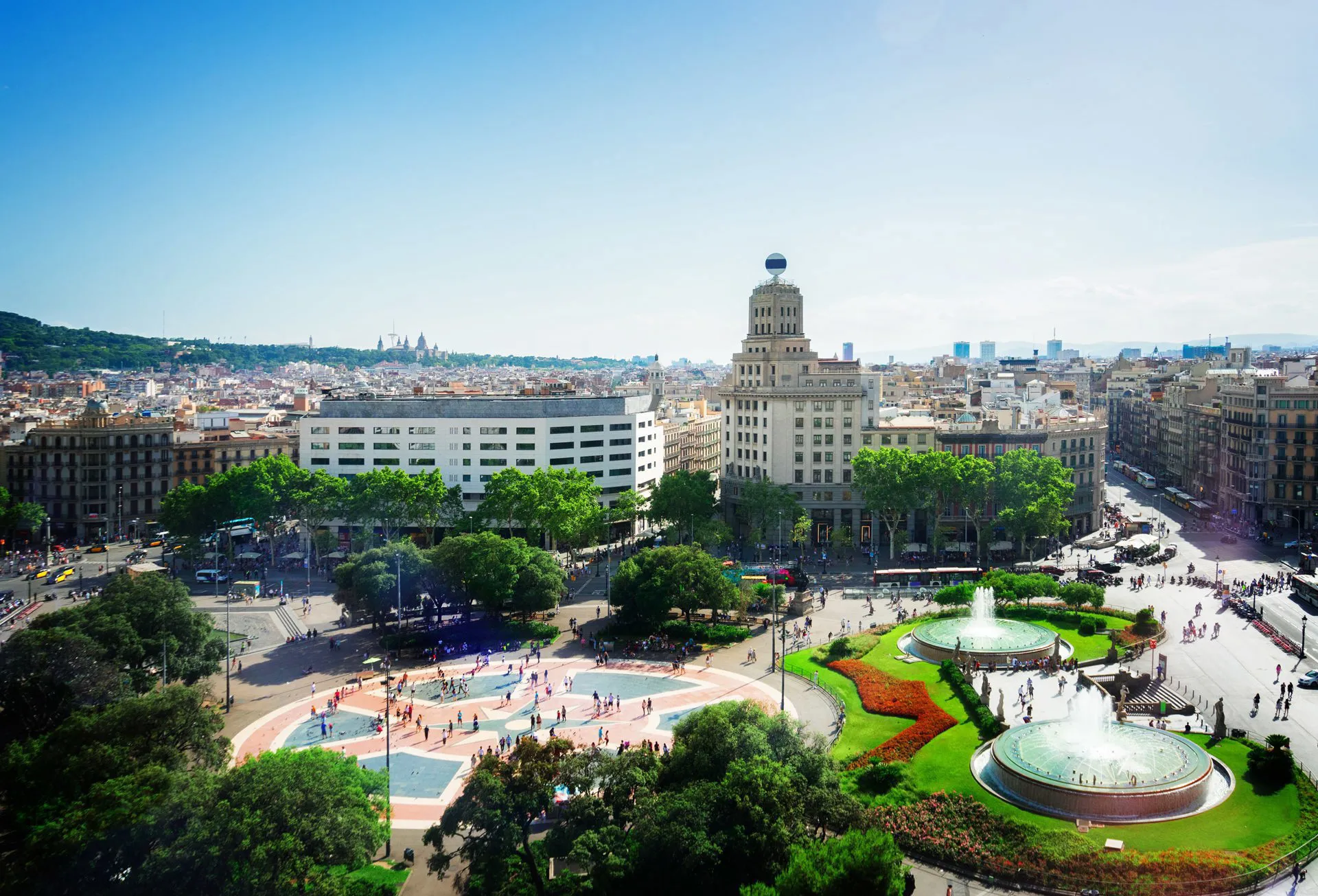 Plaza Catalunya, with fountains, trees, and green patches of grass.