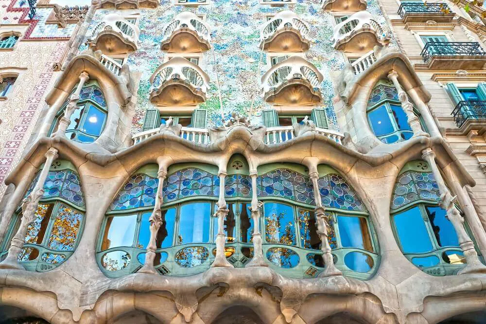The colourful exterior of Casa Batillo designed by Gaudi with many balconies and large windows.