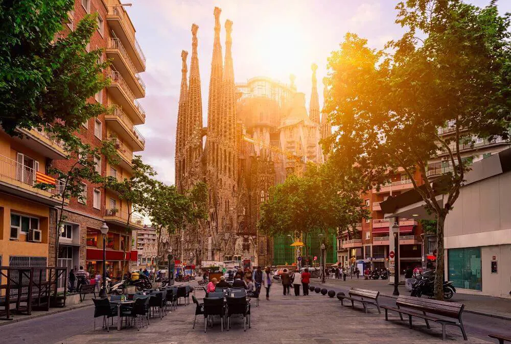 The sun shines on Barcelona Cathedral as a tree-lined street runs up towards it.