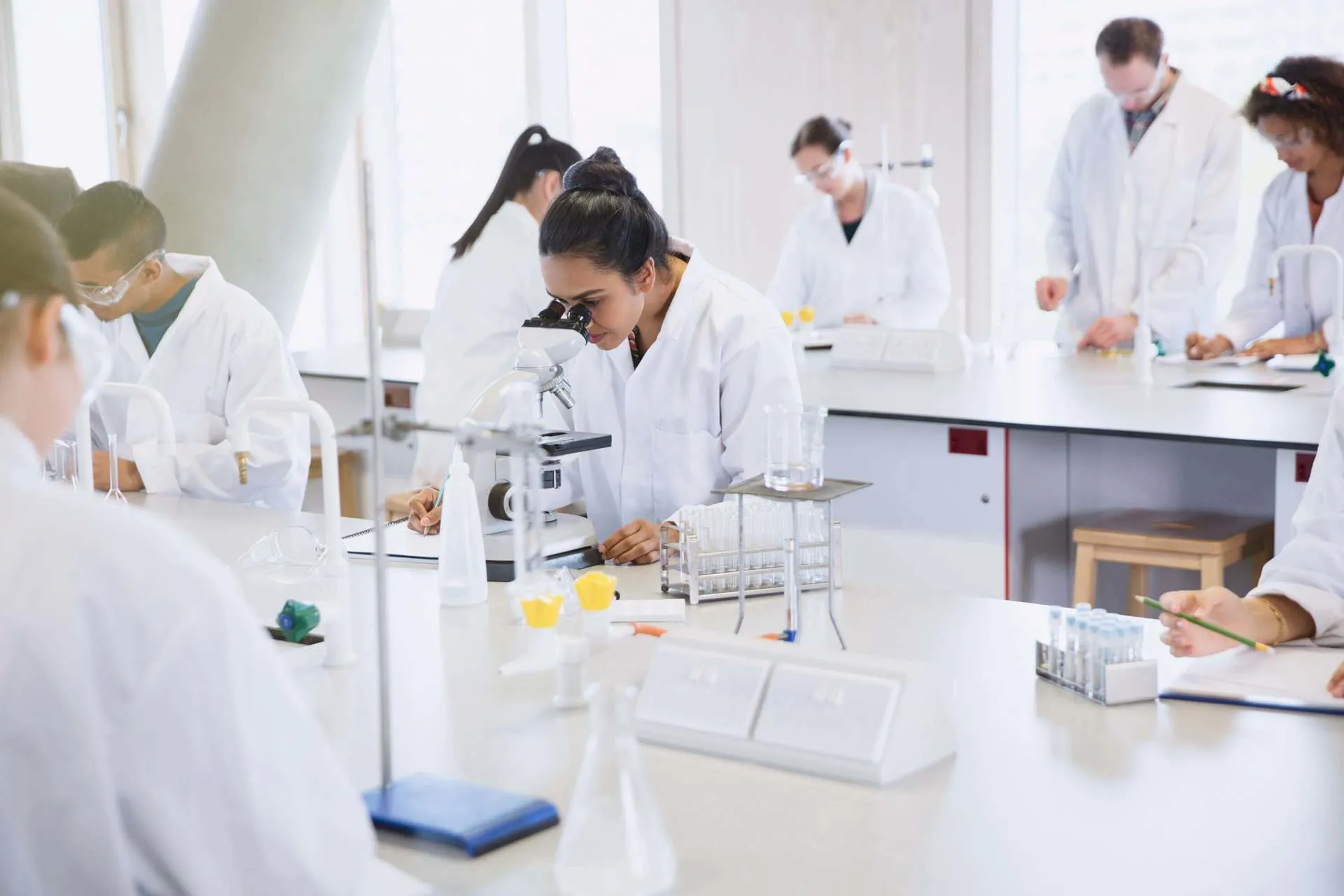 Students take part in a lab sessions as a girl looks into a microscope at the Berlin Science Museum.