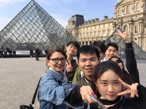 A small group of students in front of the glass pyramids of the Louvre, in Paris.