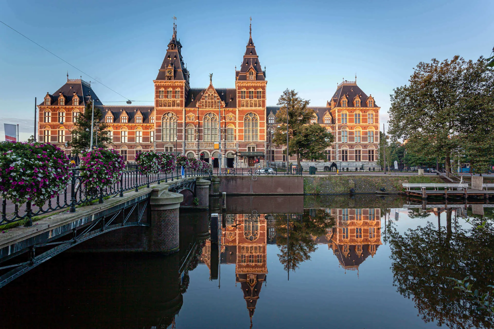 A two tower architectural building overlooking a river and bridge in Amsterdam.