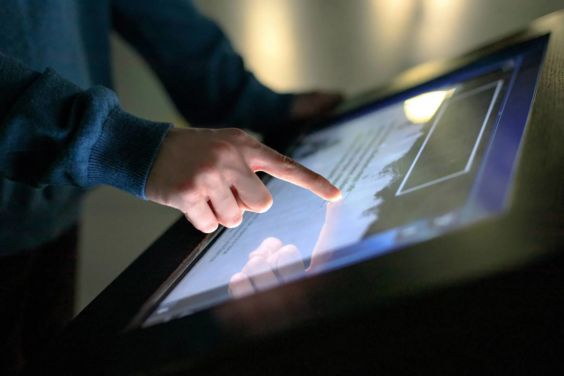A person wearing a blue jumper uses an interactive information board at the Berlin Technology Museum.