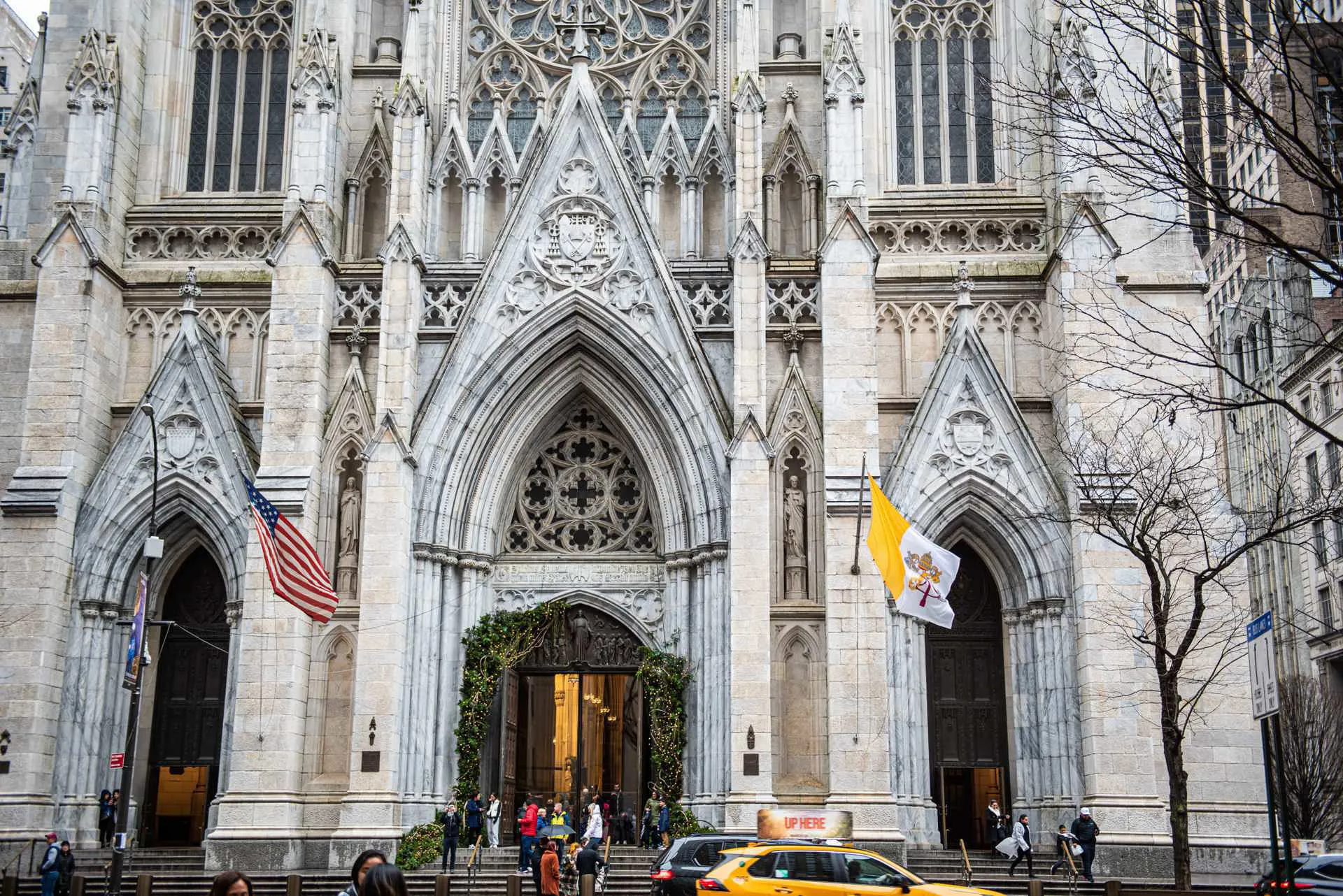 The entrance of the New York Cathedral with an American and Catholic flag outside.